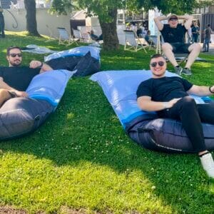 Three men relax on cushions outdoors.