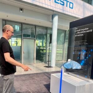 Man in front of Festo robot display in modern building