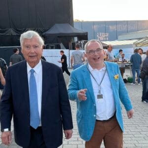 Two men smiling at an outdoor event.