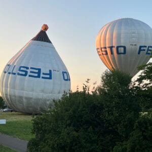 Two FESTO hot air balloons over a green park