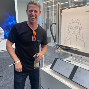 Man laughing next to a drawing machine at Festo.